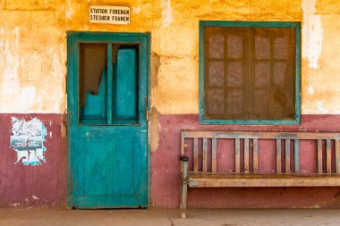 Tanzanya, Moshi 'deki terk edilmiş tren istasyonu. Alçılı duvarın önündeki yeşil kapı ve ahşap bank. Yüksek kalite fotoğraf