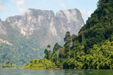 Khao Sok Ulusal Parkı, Tayland 'daki yeşil ormanlarla kaplı kireçtaşı uçurumları. Mavi göl ve uzun kuyruk teknesi, mavi gökyüzü. Yüksek kalite fotoğraf