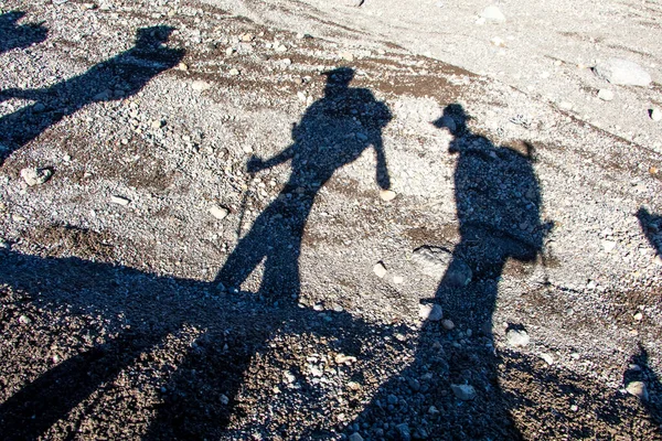 Shadow of hikers on the slope of Mount Kilimanjaro. Walking sticks, backpacks. Shadow on gravel slopes. Tanzania, Africa. High quality photo