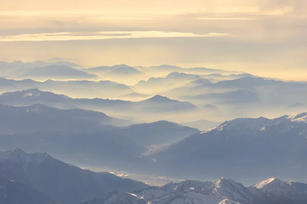 夏季阿尔卑斯山上的晨光鸟瞰图 山顶上的小雪 连绵不断地勾勒出山脉轮廓 柔和的晨光高质量的照片 — 图库照片