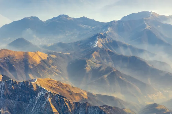 夏季阿尔卑斯山上的晨光鸟瞰图 山顶上的小雪 连绵不断地勾勒出山脉轮廓 柔和的晨光山谷里充满了云雾 高质量的照片 — 图库照片