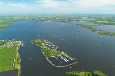 Sneek, Friesland, Hollanda 'da bulunan Sneekermeer adlı bir gölün insansız hava aracı görüntüsü. Arka planda mavi gökyüzü ve yeşil çayırlar var. Marinayla birlikte başlayın. Yüksek kalite fotoğraf