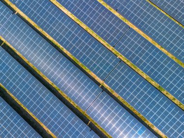 Güneş enerjisi çiftliğindeki gras üzerindeki güneş panellerini tepeden tırnağa görebiliyoruz. Mavi fotovoltaik hücrelerin altındaki çimenlerin çapraz çizgileri, PV sistemi veya güneş panelleri. Yüksek kalite fotoğraf