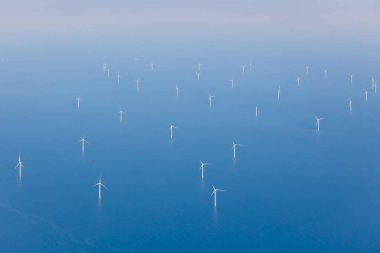 Aerial view of offshore wind farm with wind turbines on the North Sea, the Netherlands, Europe. Several large white and yellow wind turbines, wind mills on a blue, calm, flat sea. High quality photo clipart