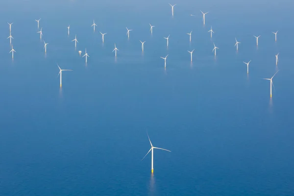 Kuzey Denizi 'nde, Hollanda' da, Avrupa 'da rüzgar türbinleriyle kıyı ötesi rüzgar tarlalarının havadan görüntüsü. Birkaç büyük beyaz ve sarı rüzgar türbini, mavi, sakin, düz deniz üzerindeki rüzgar değirmenleri. Yüksek kalite fotoğraf