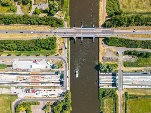 Topdown view of an navigable aquaduct under construction with a small yacht, boat or pleasure craft. Prinses Margriettunnel and draw bridge near Sneek, Uitwellingerga, Friesland. High quality