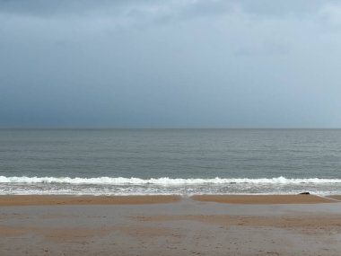 İngiltere, Newcastle 'daki Whitley Körfezi' nde kumlu ve dalgalı sahilde kara yağmur bulutları var. Yüksek kalite fotoğraf