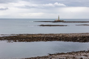 St. Marys Deniz Feneri. Basalt yolu alçak gelgitte bir dizi bazalt rıhtımla ve İngiliz sahilinin sadece düz, sakin bir deniziyle. Whitley Körfezi, Newcastle, İngiltere
