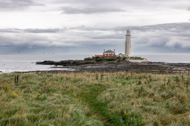 St. Marys Deniz Feneri 'nin deniz seviyesinin altında bazalt yolu ve deniz kenarında geniş bir yel değirmeni var. Alternatif yeşil, yenilenebilir enerji ve elektrik için, sadece İngiliz kıyılarında. Whitley Körfezi, Newcastle, İngiltere. 