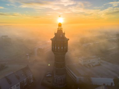 Gündoğumunda tarihi su kulesiyle Frizya 'nın Sneek şehrinde insansız hava aracı görüntüsü. Parlak turuncu renkler ve şehrin sokaklarında biraz sis. Yüksek kalite fotoğraf