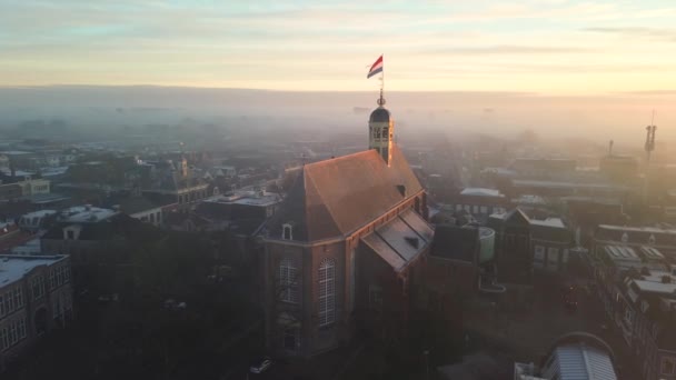 日出时分 无人机看到斯内克镇对面 教堂顶上挂着荷兰国旗 城市街道上明亮的橙色和一点雾气 高质量的4K镜头 — 图库视频影像