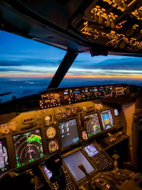 Yolcu uçuşundaki bir uçağın gece kokpiti görüntüsü. Kaptan, bir jet uçağının enstrümanlarına ve kontrollerine doğru bakın. Gün batımı görünüyor. Yüksek kalite fotoğraf