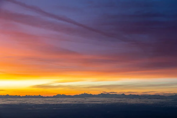 Aerial image of colourful morning sky with Cirrus clouds above Swiss Alps. Jagged, snowy mountain peaks, through the clouds, bright, colours in the sky.High quality photo