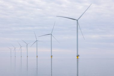 Sahil açıklarında rüzgar türbinleri ya da düz, sakin bir denizde rüzgar olmayan rüzgar değirmenleri. Gri bulutlu gökyüzü. Yüksek kaliteli fotoğraf.
