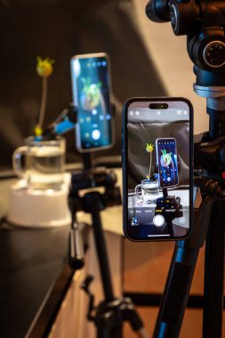 Telefonun görüntüsü, tripodun üzerinde telefon kameralı telefonun fotoğrafını çekiyor stüdyo ortamında çiçeklerle dolu bir hayatın görüntüsünü çekiyor. Yüksek kalite fotoğraf