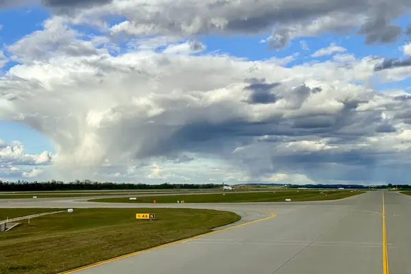 机场的灰色跑道滑行道上有黄色的标志和令人印象深刻的雷雨云 高质量的照片 图库图片