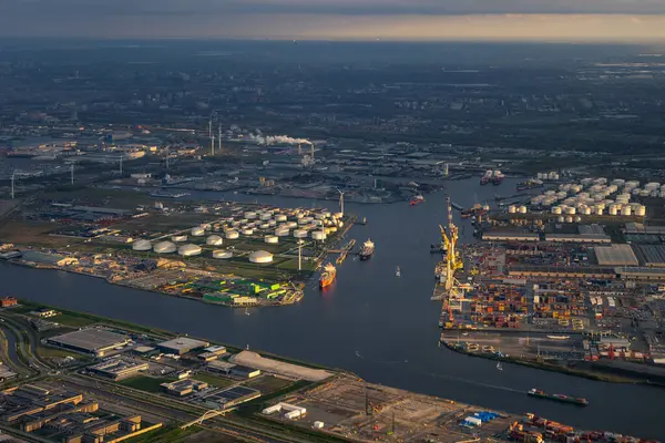 晚霞从空中俯瞰阿姆斯特丹港口或港口 起重机 集装箱都在岸上 在最后一缕阳光下 通往城市的运河和水道 高质量的照片 免版税图库图片
