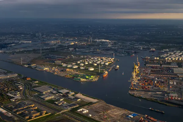 晚霞从空中俯瞰阿姆斯特丹港口或港口 起重机 集装箱都在岸上 在最后一缕阳光下 通往城市的运河和水道 高质量的照片 图库图片