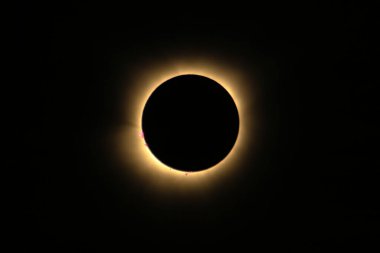 Total solar eclipse of April 8th 2024 with the sun peaking from behind the moon creating. a diamond ring effect. Red prominences and bright corona during totality. High quality photo clipart