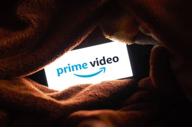 Battaniyenin altında cep telefonuyla Amazon Prime videosu izlemek.