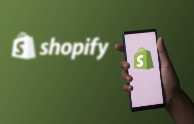 Dhaka, Bangladeş - 06 Aralık 2023: Ekranda alışveriş uygulaması olan bir el telefonu tutuyor. Shopify uygulaması bir finans şirketi..