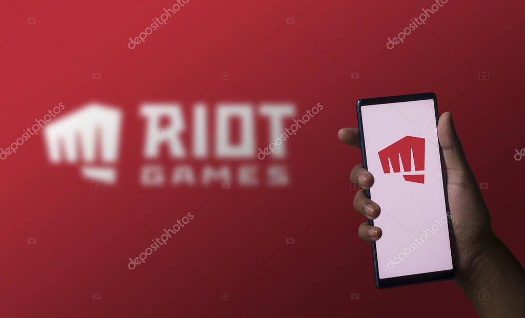 Dhaka, Bangladesh- 07 December 2023: A hand holding a phone with the Riot games logo on the screen.