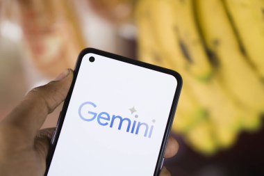 Dhaka, Bangladesh - 27 December 2023: Hand holding a phone with Google Gemini AI chatbot Gemini is a family of multimodal large language models developed by Google. clipart