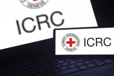 Dhaka, Bangladeş - 19 Ocak 2024: Akıllı telefon ve arka plan dizüstü bilgisayarı ICRC logosu. Uluslararası Kızılhaç Komitesi insani bir organizasyondur..