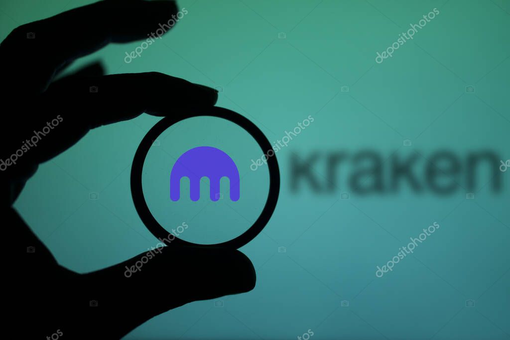 Dhaka, Bangladesh - 25 January 2024 :  A person holding a magnifying glass to inspect the logo of Kraken. Kraken is a United States based cryptocurrency exchange platform.