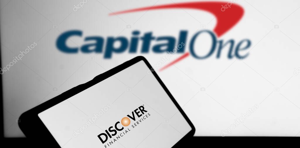 Dhaka, Bangladesh- 22 February 2024: Discover Financial Services logo is displayed on a smartphone and the Capital One Financial logo on the background.