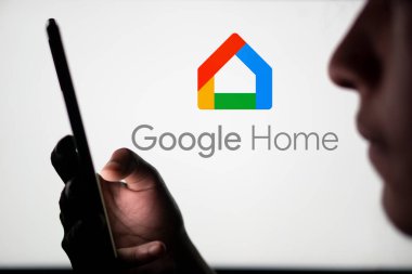 Dhaka, Bangladeş - 23 Temmuz 2024: Google Home logosu akıllı telefon tutan bir adamın arkasında sergileniyor.