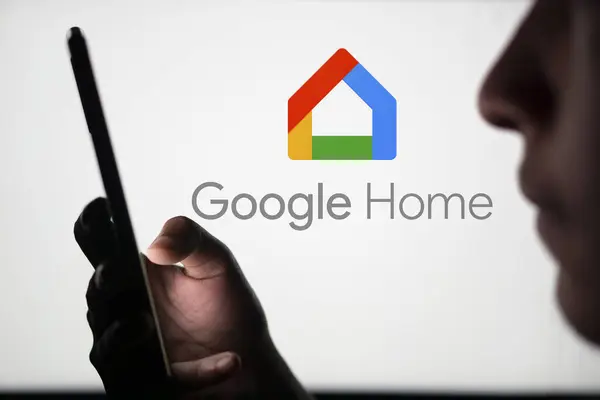 Dhaka, Bangladeş - 23 Temmuz 2024: Google Home logosu akıllı telefon tutan bir adamın arkasında sergileniyor.
