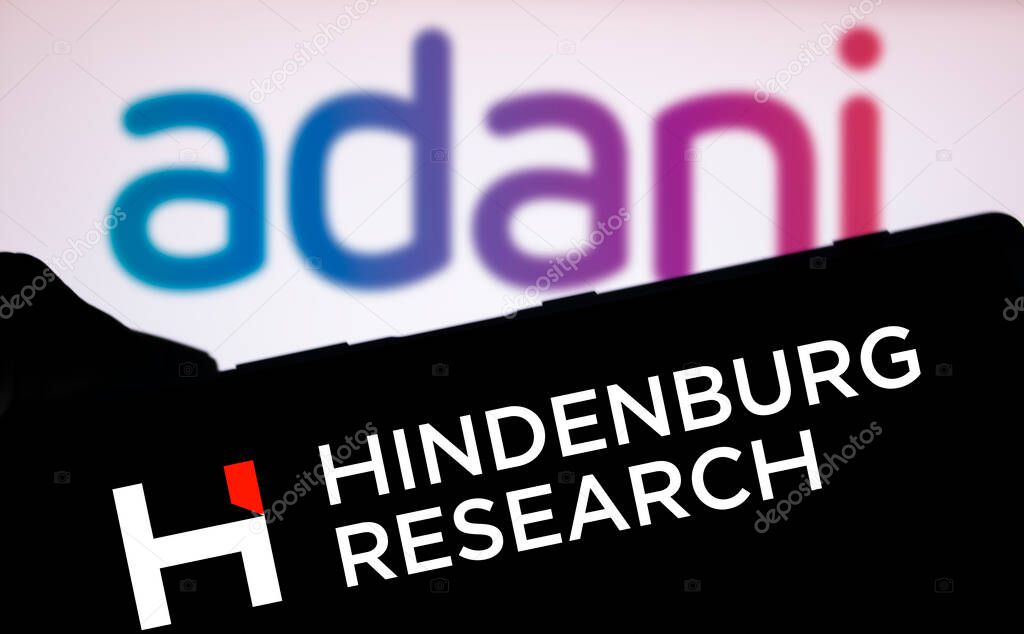 Dhaka, Bangladesh- 18 Aug 2024: The Hindenburg Research logo is displayed prominently on a smartphone screen in the foreground, with the Adani logo blurred in the background.