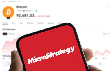 Dhaka, Bangladeş - 27 Kasım 2024: Mikrostrateji logosu akıllı telefon ve arka planda Bitcoin fiyatı gösterilir.