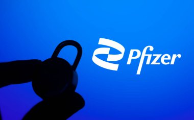 Dhaka, Bangladeş - 11 Ocak 2025: Bir el pfizer logosunun önünde kilitli bir asma kilidi tutuyor. Pfizer Inc., ABD 'li çok uluslu ilaç ve biyoteknoloji şirketidir..