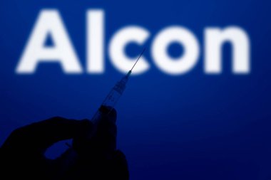 Dhaka, Bangladesh- 28 Dec 2024: A gloved hand holding a syringe in front of the Alcon logo. Alcon Inc is a Swiss-American pharmaceutical and medical device company specializing in eye care products. clipart