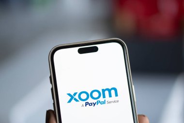 Dhaka, Bangladesh- 18 Jan 2025: xoom logo is displayed on smartphone. Xoom Corporation is an electronic funds transfer and remittance provider. clipart