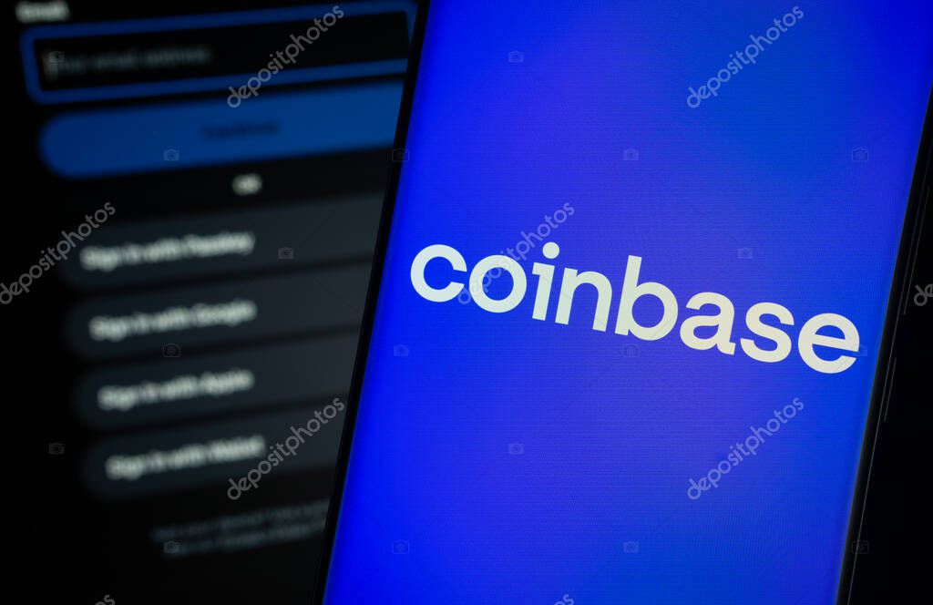 Dhaka, Bangladesh- 05 March 2025: Coinbase logo is displayed on a smartphone screen, with the coinbase login page visible on a computer screen in the background.
