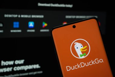 Dhaka, Bangladeş - 08 Mart 2025: DuckGo logosu bir akıllı telefon ekranında gösteriliyor, DuckDuckGo web sitesi arka planda bir bilgisayar ekranında görünüyor.