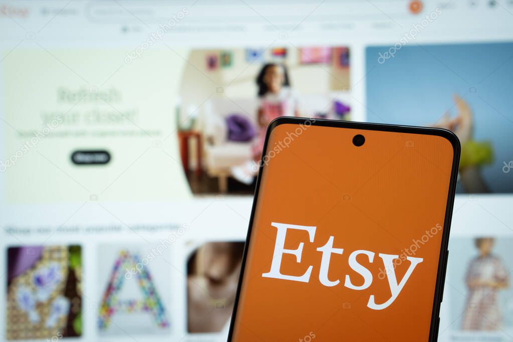 Dhaka, Bangladesh- 08 March 2025: Etsy logo is displayed on a smartphone screen, with the Etsy website visible on a computer screen in the background.