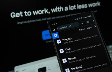 Dhaka, Bangladeş - 16 Mart 2025: Dropbox uygulaması akıllı telefon ekranında görüntülenir ve web sitesi indirme kutusu arka planda bir bilgisayar ekranında görünür.