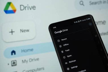 Dhaka, Bangladeş - 16 Mart 2025: Google sürücünün uygulaması akıllı telefon ekranında görüntülenir ve web sitesi google sürücüsü arka plandaki bir bilgisayar ekranında görünür.