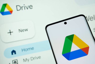 Dhaka, Bangladeş - 16 Mart 2025: Google sürücünün uygulaması akıllı telefon ekranında görüntülenir ve web sitesi google sürücüsü arka plandaki bir bilgisayar ekranında görünür.