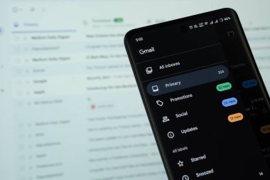 Dhaka, Bangladeş - 16 Mart 2025: Gmail 'in logosu akıllı telefon ekranında gösteriliyor ve web sitesi gmail arka plandaki bilgisayar ekranında görülebiliyor.