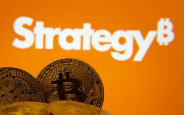 Dhaka, Bangladeş - 27 Mart 2025: MikroStrateji logosu arkaplanda görünen ekranda görünen Bitcoin paralarının yakın çekimi.