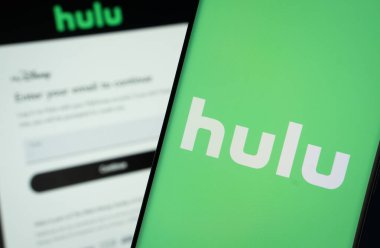 Dhaka, Bangladeş - 16 Mart 2025: hulu logosu bir akıllı telefon ekranında gösterilir, arka planda bir bilgisayar ekranında hulu giriş sayfası görünür..
