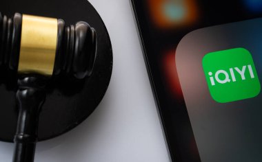 Dhaka, Bangladeş - 17 Mart 2025: Bir yargıcın tokmağının yanında iqiyi uygulamasını gösteren iPad ekranına yakın çekim.