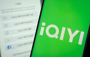 Dhaka, Bangladeş - 17 Mart 2025: Iqiyi logosu bir akıllı telefon ekranında gösterilir, arka planda bir bilgisayar ekranında Iqiyi giriş sayfası görünür.