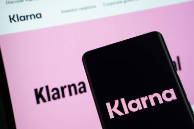 Dhaka, Bangladeş - 17 Mart 2025: Klarna logosu akıllı telefon ekranında gösteriliyor ve klarna web sitesi arka planda bir bilgisayar ekranında görülebiliyor.