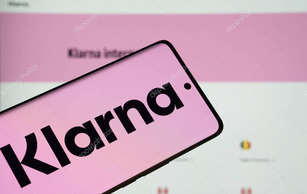 Dhaka, Bangladesh - 17 March 2025: The logo of the klarna is displayed on a smartphone screen, and the website klarna is visible on a computer screen in the background.